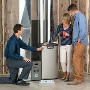 technician showing new furnace install to homeowners